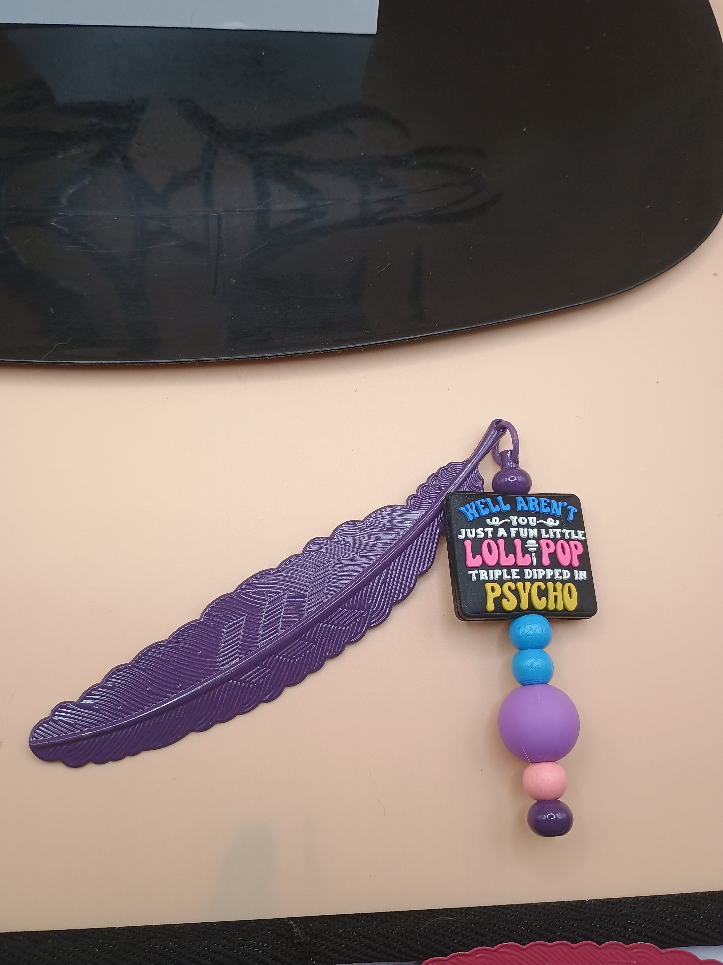 “Fun Little Lollipop Triple Dipped in Psycho” Feather Bookmark – Purple Metal Beaded Bookmark